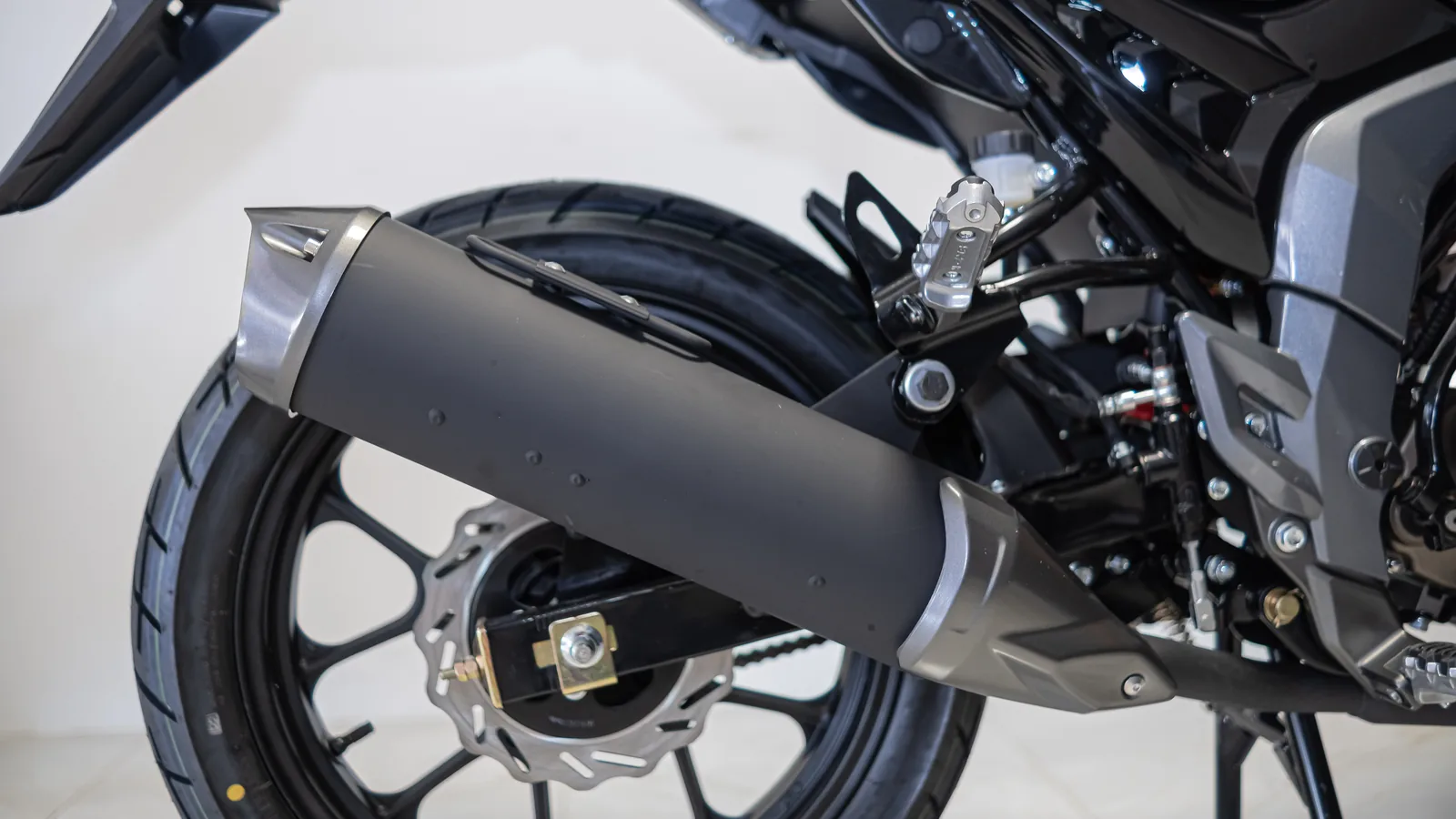 Detalhe do escapamento, disco de freio e roda traseira da moto Virtoo